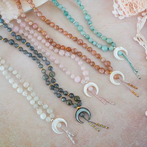 Set of beaded necklaces with moon pendants on a textured surface