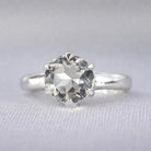 A sterling silver ring featuring a large, round, faceted white topaz gemstone in a prong setting.